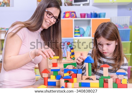 Teacher with Cute Girl Building With Toy Blocks