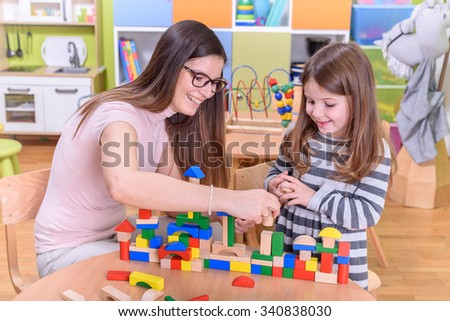 Happy Kid With Kindergarten Teacher Plays with Building Blocks