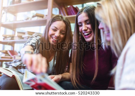 Group of smiling female students with books at school cafeteria