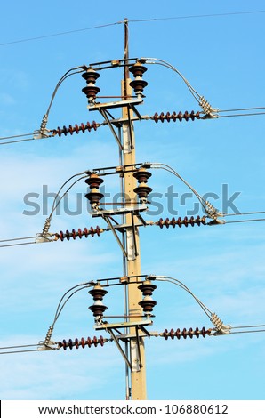 Energy and technology: electrical post by the road with power line cables against bright blue sky providing copy space.