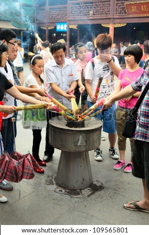 SHANGHAI, CHINA - JUL 14: Devotees light incense bundles for offering to Qin Yubo on Jul 14, 2012 in Shanghai, China. The emperor bestowed upon him the honor of being a city god in Shanghai