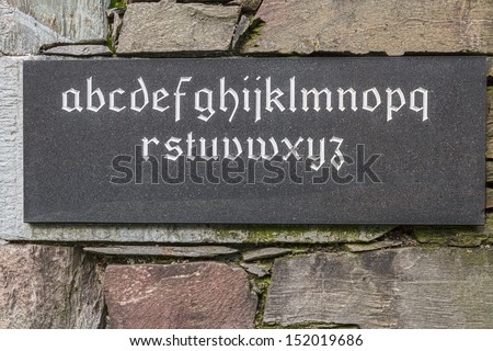 Alphabet Carved into Black Stone Tablet on a Stone Wall