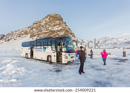 REYKJAVIK, ICELAND - January 18, 2015: Tour bus having a break in front of Eyjafjallajokull Mountain. Reykjavik Excursions is a leading organizer of coach and bus tours in Iceland.