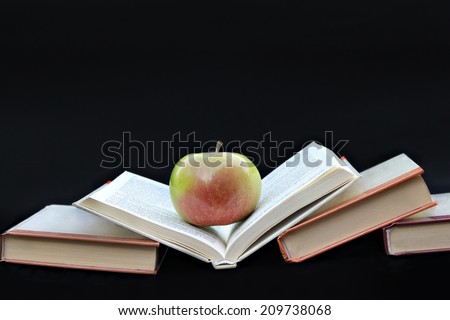 Books  Pile of books with apple on black background