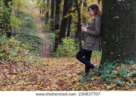 In the forest, Young woman in the park looking in the mobile phone