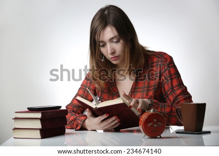 Study time,  Young woman reading with stack of text books.