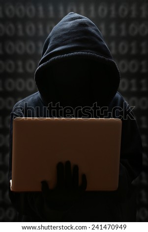 Silhouette of a hacker looking in monitor, Hacker typing on a laptop with binary code in background