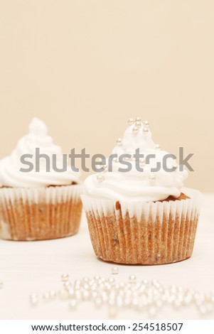 Cupcakes with whipped cream,  White cupcakes with decorative silver sprinkles. Shallow dof.