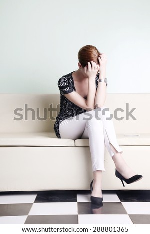Young woman sitting with hands over her face, bored, worried or stressed