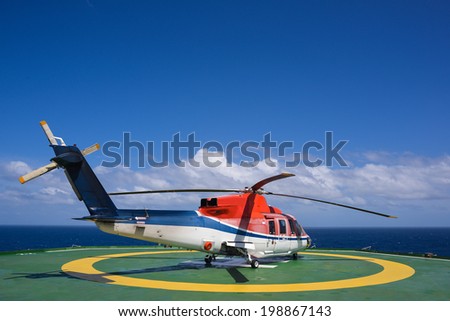 Shut down helicopter on oil rig helipad with blue sky