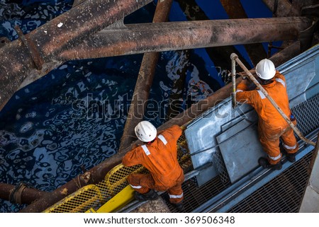 Two workers at jack up oil rig leg when checking everything in rig move operation
