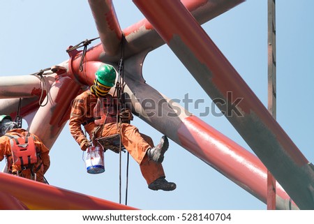 Workers working at height to paint the jack up oil and gas rig with full personnel protective equipment