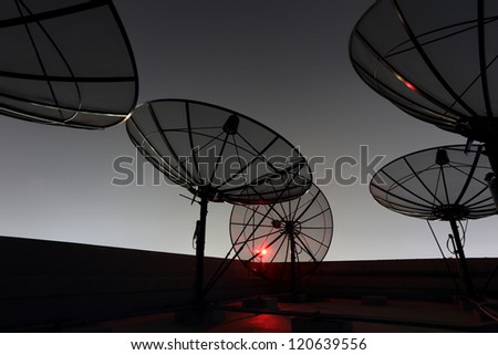black antenna communication satellite dish over twilight sky in cityscape