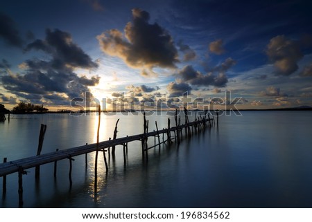 Bamboo bridge on water sea with sunset sky background