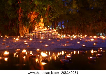 Buddhist monk fire candles to the Buddha with beautiful water reflection in Phan Tao Temple, Chiangmai, Thailand