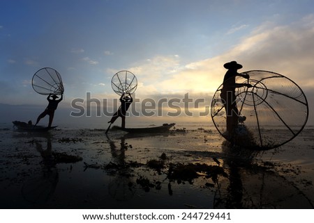 Silhouette of People fishing on Lake Inle in sunrise with fog at Burma, Myanmar