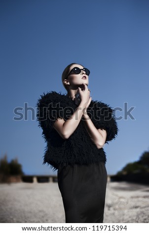 young sexy fashionable woman in a black clothing and sunglasses indoor