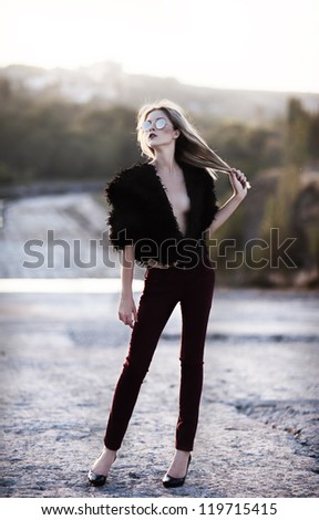 young sexy fashionable woman in a black clothing and sunglasses indoor