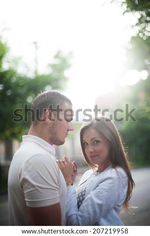 Outdoor lifestyle portrait of young couple in love standing in old town on the street behind sunset