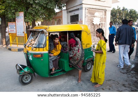 DELHI - DECEMBER 21: A family gets into an auto rickshaw running on natural gas on December 21, 2009 in Delhi, India. Auto rickshaws running on natural gas are painted green and yellow.