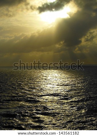 the sun over the caribbean ocean with sunlight streaming through the clouds