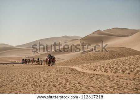 DUNHUANG, CHINA - JUNE 29: Camel safari takes tourists across the famous Mingsha sand dunes on June 29, 2012 outside Dunhuang in the Gobi desert. Dunhuang is located on the historic Silk road.