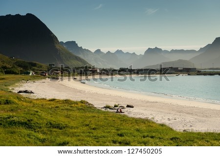 RAMBERG, NORWAY - JULY 5: Two tourists enjoying the summer weather in northern Norway on July 5, 2011 at the beach in Ramberg, Lofoten. Ramberg attracts tourists due to it\'s famous arctic white beach.