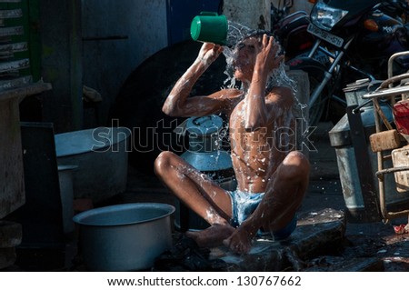 AGRA, INDIA - FEBRUARY 5: A young man washes himself in the street on February 5, 2011 in a village near Agra. One third of India\'s population fall below the World Bank\'s international poverty line.
