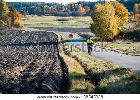 RISINGE, SWEDEN - OCTOBER 13: Bicycle rider struggles uphill on a countryside road on October 13, 2013 in Risinge, Sweden. Bicycles are a popular way of transportation in Scandinavia.