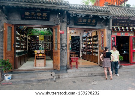 BEIJING, CHINA - JUNE 19: Chinese chat outside stores on the main street of the Jingyang Hutong on June 19, 2012 in Beijing. The Hutongs provide a glimpse of life in Beijing centuries ago.