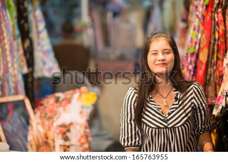 HUA HIN, THAILAND -  JANUARY 17: Young Thai woman sells clothes in a stand at the night market on January 17, 2013 in Hua Hin. The famous night market in Hua Hin is a major tourist attraction.