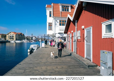 SMOGEN, SWEDEN  SEPTEMBER 3: Woman walks a dog at the boardwalk on September 3, 2014 in Smogen. The boardwalk Smogen is a popular tourist attraction in the famous fishing village Smogen.