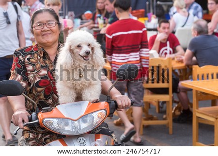 HUA HIN, THAILAND JANUARY 18: Thai woman with a happy dog on a motorbike at the  night market on January 18, 2015 in Hua Hin. The famous night market in Hua Hin is a major tourist attraction.