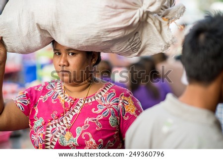 YANGON, MYANMAR - FEBRUARY 10: Burmese woman carries a heavy load in Chinatown on February 10, 2014 in Yangon. Myanmar is ethnically diverse with 51 million inhabitants belonging to 135 ethnic groups.