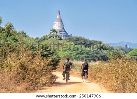 BAGAN, MYANMAR - FEBRUARY 7: Tourists on bikes exploring the archeological site on February 7, 2014 in Bagan. Bagan is famous for its thousands of temples, pagodas and stupas.