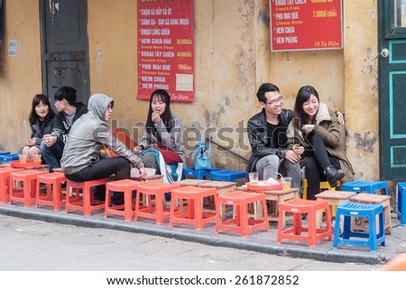 HANOI, VIETNAM   FEBRUARY 10: Vietnamese youngsters at an outdoor restaurant in the old quarter on February 10, 2015 in Hanoi. The 36 old streets of the old quarter are a major tourist attraction.