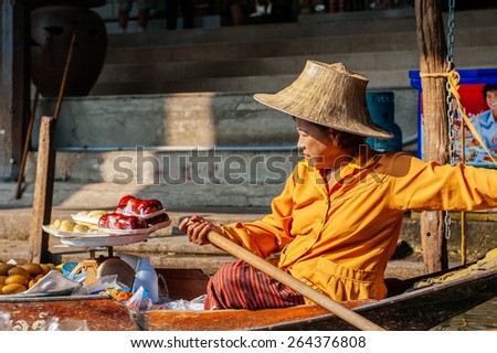 DAMNOEN SADUAK, THAILAND  FEBRUARY 2: Thai woman sells fruit from a boat at the Floating Market on February 2, 2009 in Damnoen Saduak. The floating market is a major tourist attraction.