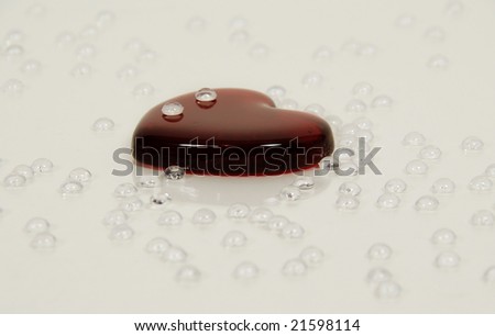 Tear drops of wet liquid on red glass heart