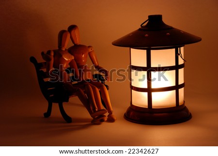 Sitting on a bench in front of a bright lantern in the evening