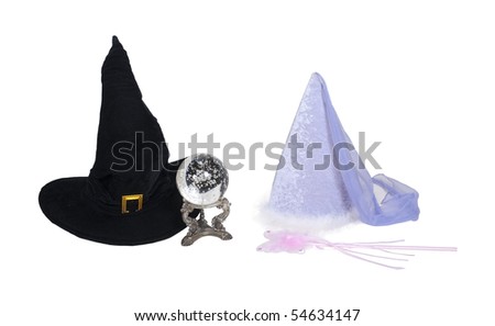 Fantasy good and evil shown by a traditional large pointed black witch hat with crystal ball with a princess hat with fairy wand - path included