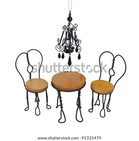 Black chandelier with black crystals hanging down over a bistro setting of chairs and table - path included