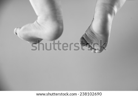 Black and white image of a childs or babies feet hanging in the air