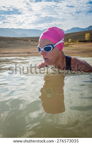 An active female is seen swimming across a dam while wearing a pink swimming cap