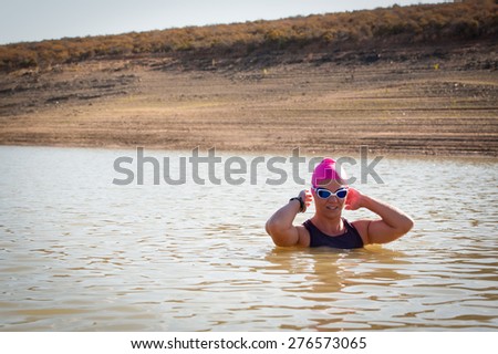 An active female is seen swimming across a dam while wearing a pink swimming cap