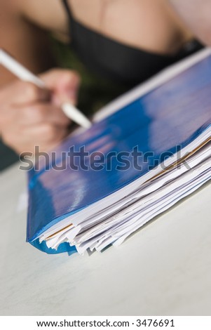 stack of papers on the front and pencil in hand on background