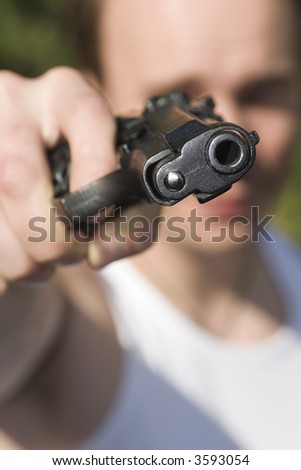 A man holding a gun and pointing it at the camera.
