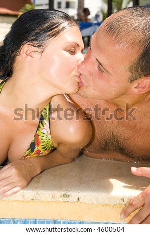 An attractive young couple kissing by the pool