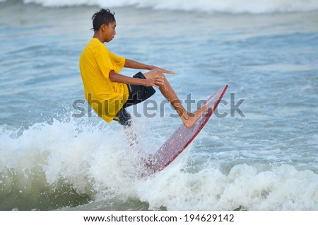 KUANTAN - DECEMBER 29: unidentified surfer in action catching waves in evening at Teluk Cempedak beach on December 29, 2012 in Kuantan, Pahang, Malaysia.