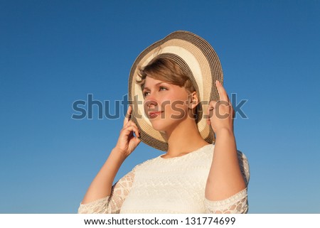 Portrait of  young woman near sea holding her hat and looking ahead