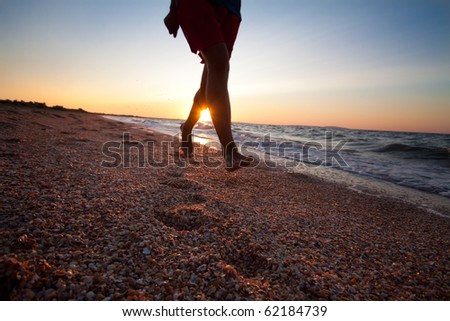 Legs and feet of man running at the beach on beautiful summer sunset